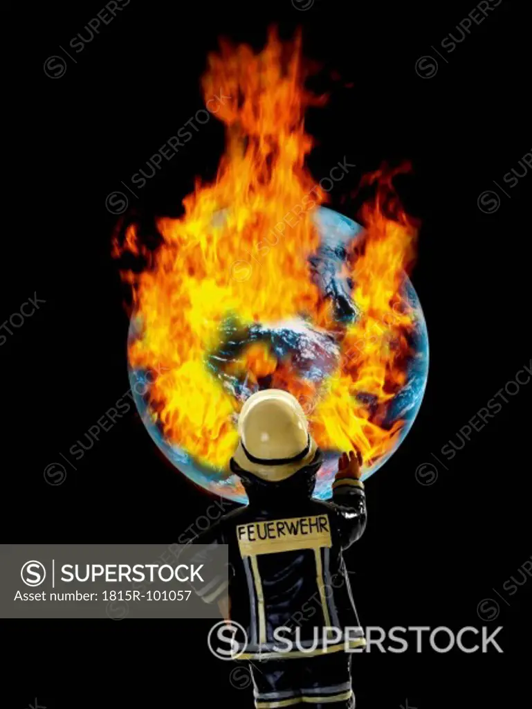 Fireman figurine in front of earth with burning fire, close up