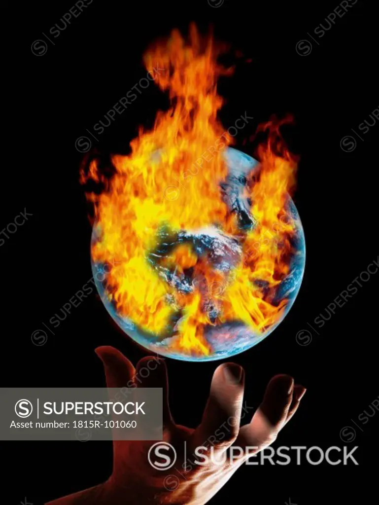 Hand reaching below earth with burning fire against black background