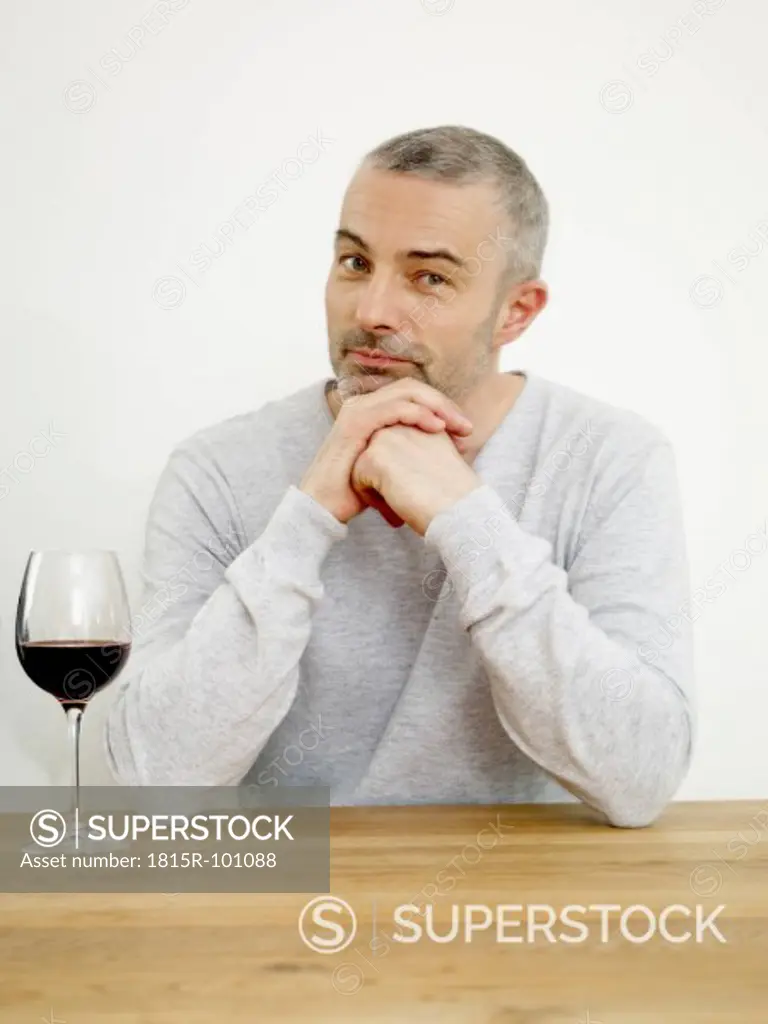 Germany, Cologne, Mature man with wine in kitchen, portrait