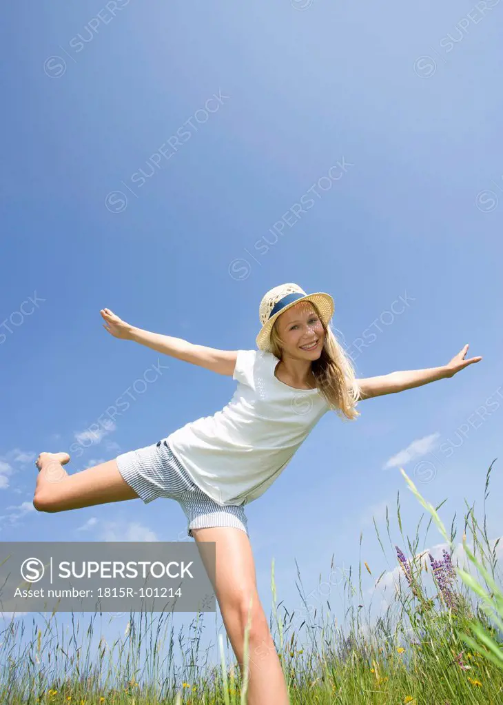 Austria, Teenage girl doing gymnastics in field, smiling, portrait