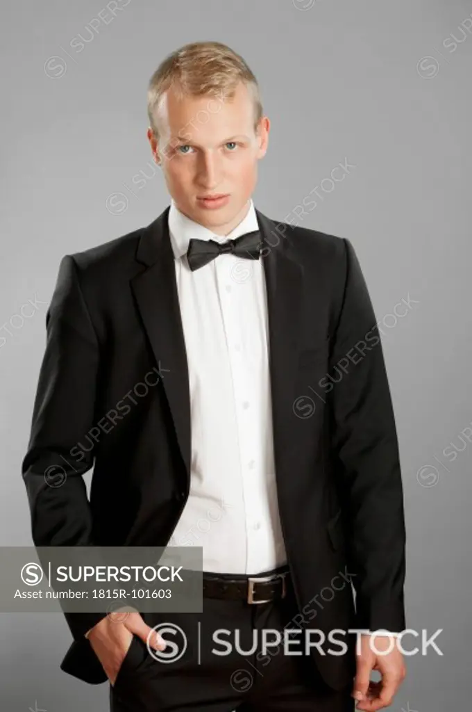 Young man in black suit against gray background