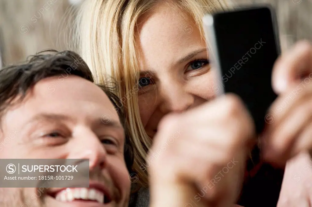 Couple watching cell phone, smiling, close up