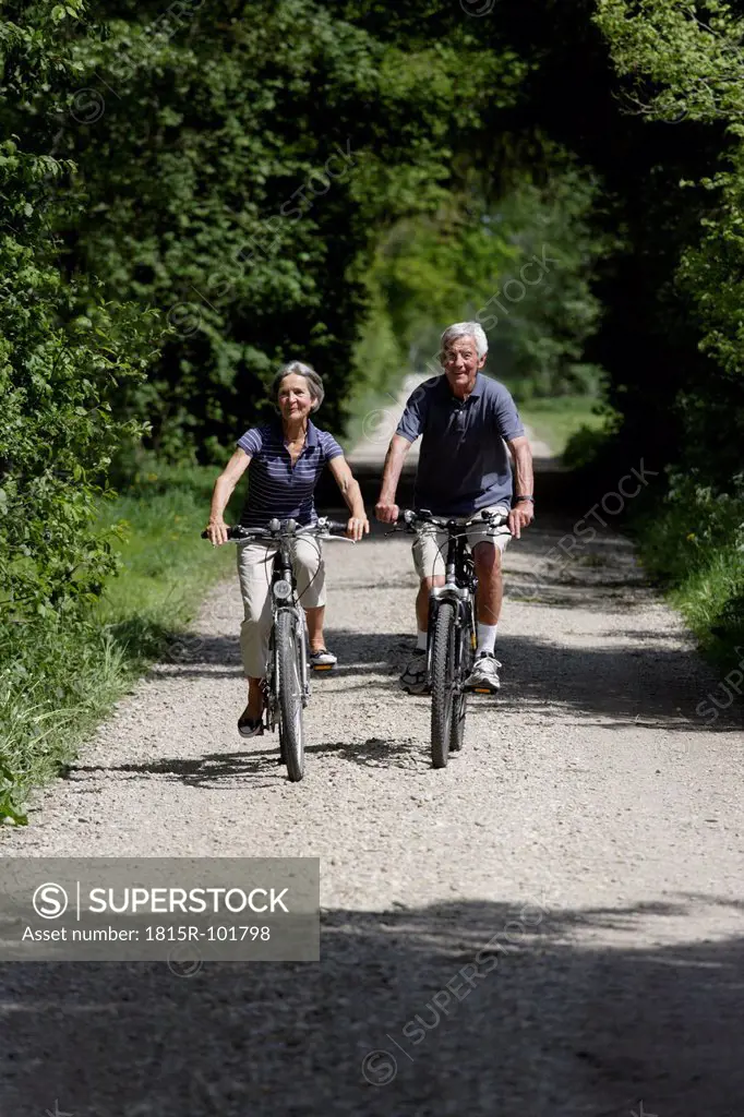 Germany, Bavaria, Senior couple cycling through single track