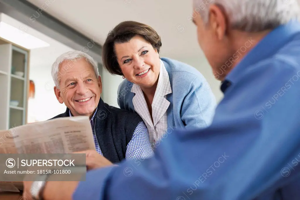 Germany, Leipzig, Senior man reading newspaper, man and woman smiling