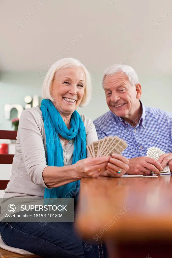 Germany, Leipzig, Senior man and woman playing card game, smiling