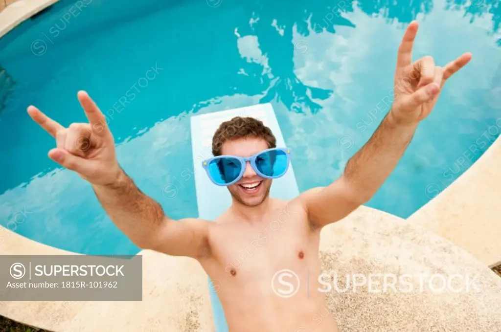 Spain, Mallorca, Young man with funny glasses on diving board, smiling
