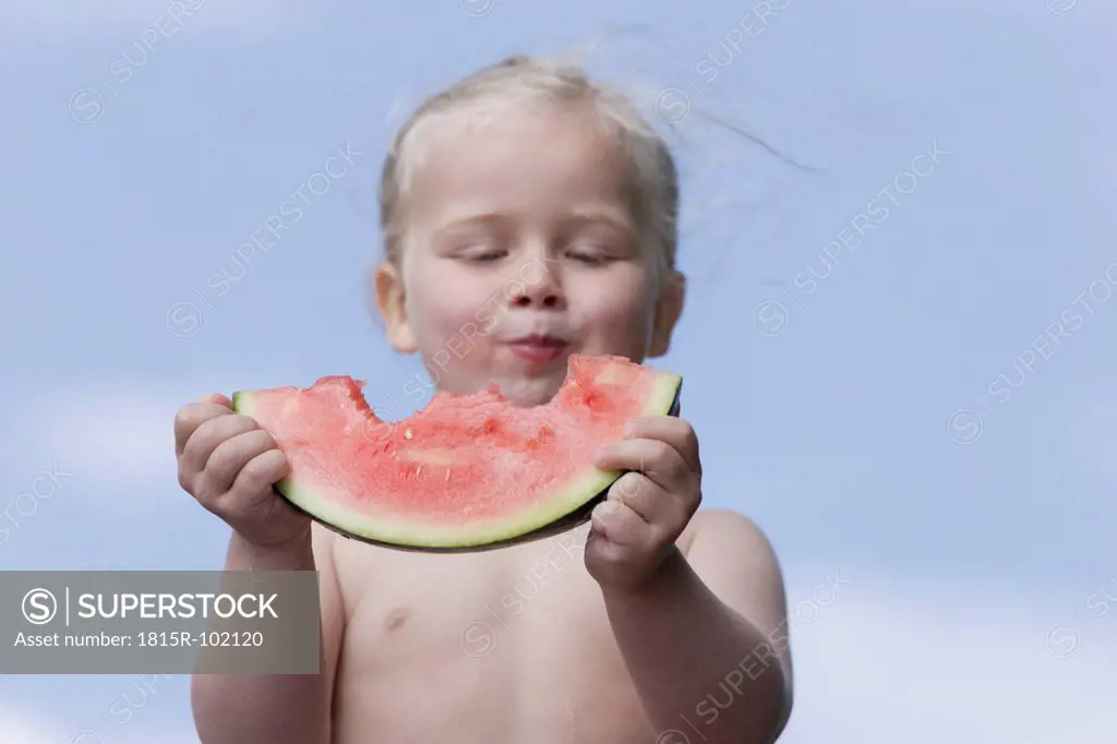 Germany, Bavaria, Girl eating piece of watermelon