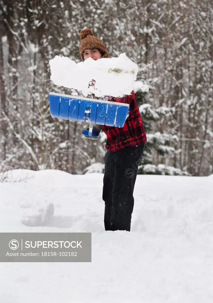 Austria, Young man shoveling snow, portrait