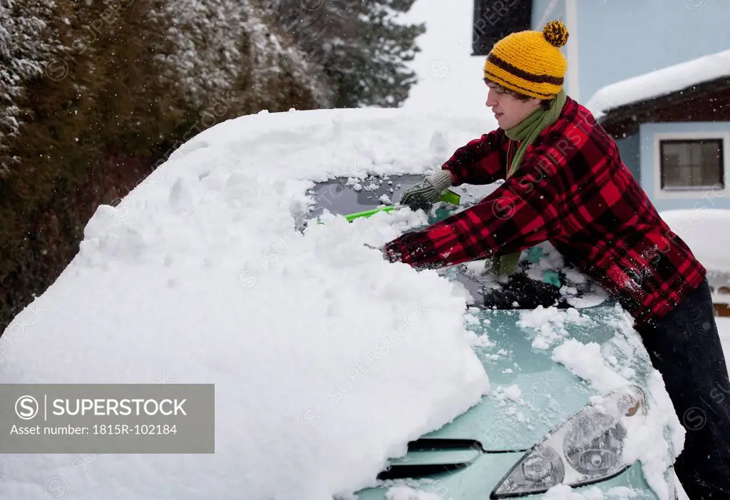 Austria, Young man cleaning snow on car