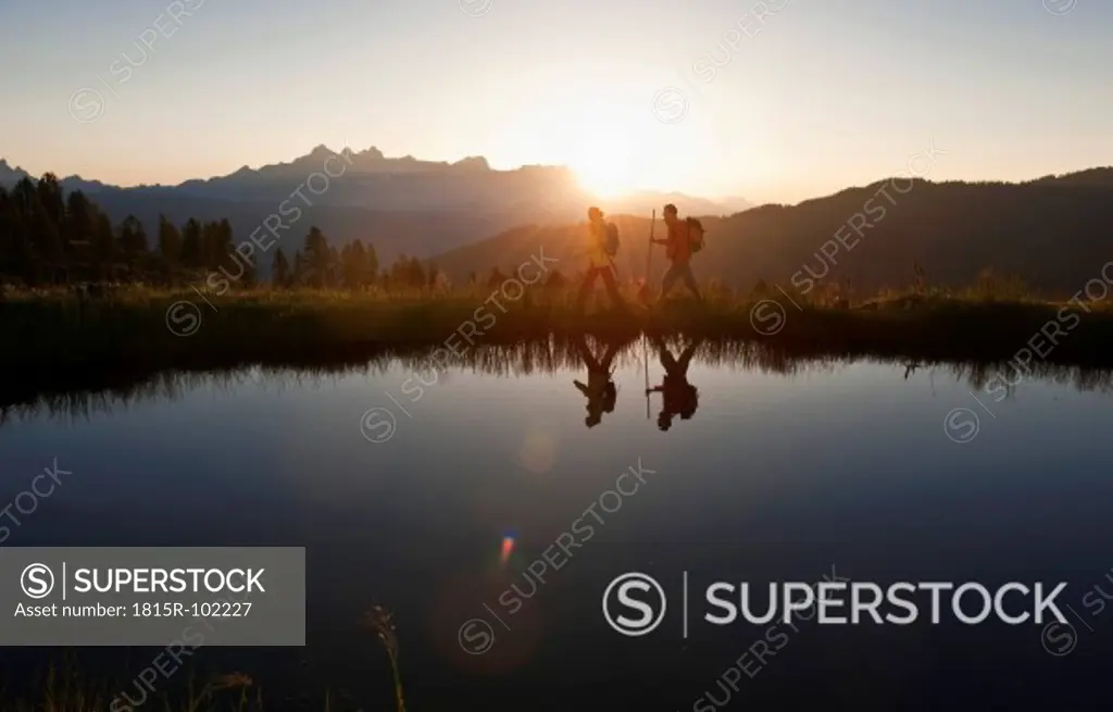 Austria, Salzburg, Couple walking near mountain lake at sunrise