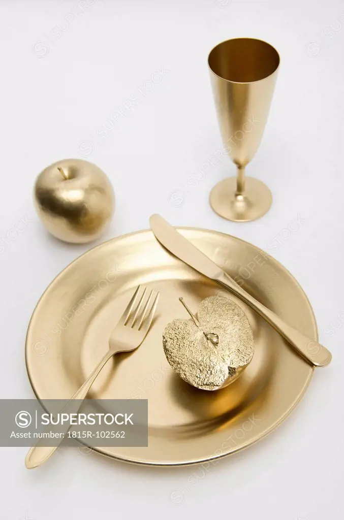 Golden cutlery with apple on white background