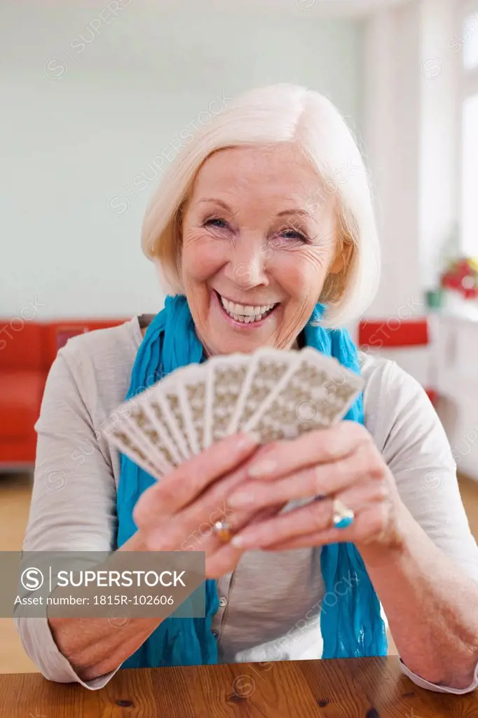 Germany, Leipzig, Senior woman playing cards, smiling