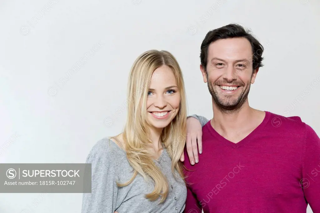 Couple smiling against white background, portrait