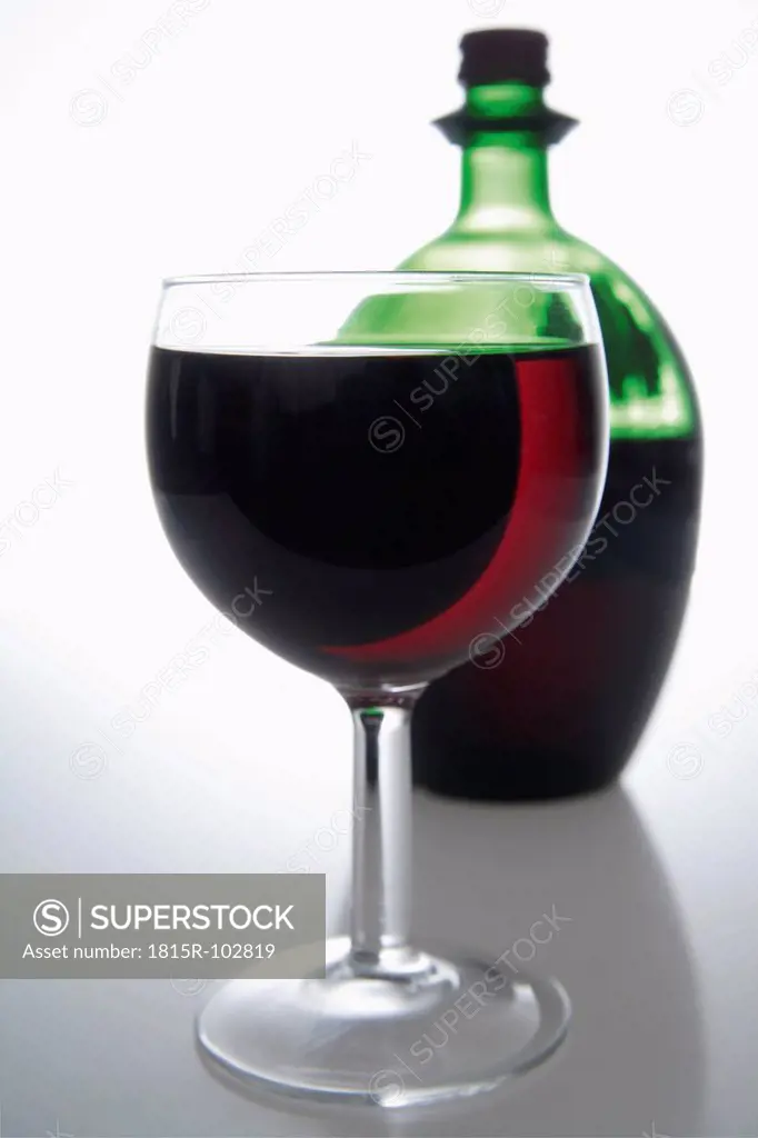 Red wine in glass and bottle on grey background