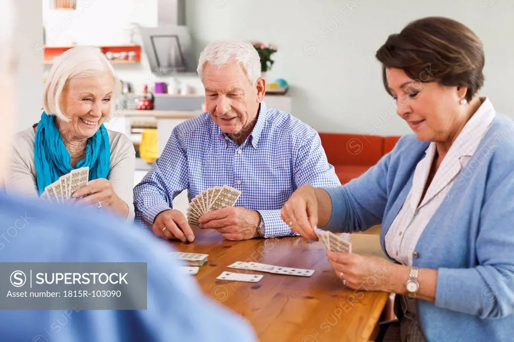 Germany, Leipzig, Senior men and women playing cards, smiling