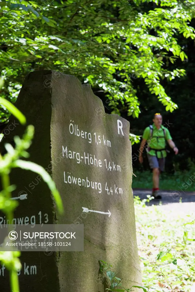 Europe, Germany, North Rhine Westphalia, Hiking trail sign with hiker in background