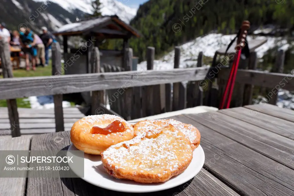 Austria, Styria, Gfolleralm, Donut in plate with people in background