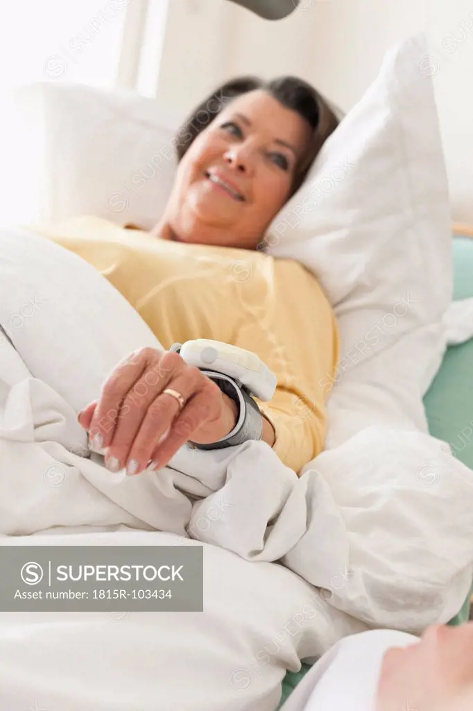 Germany, Leipzig, Senior woman lying on medical bed, smiling