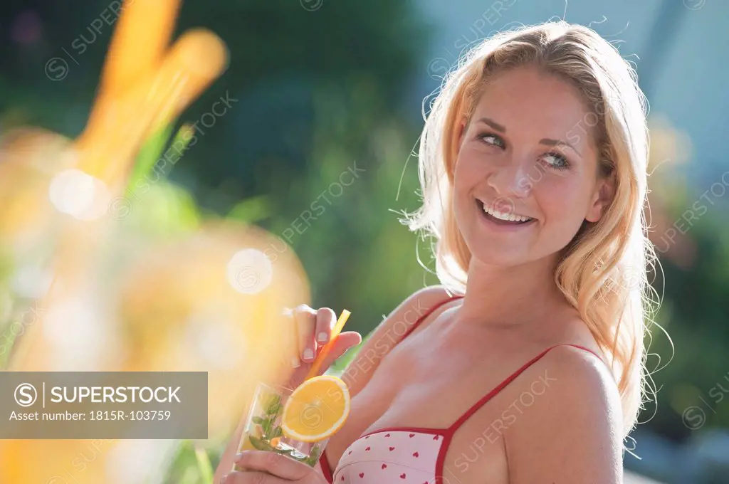 Austria, Salzburg County, Young woman with drink near pool