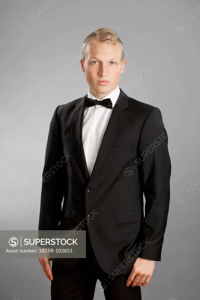 Young man in black suit against gray background