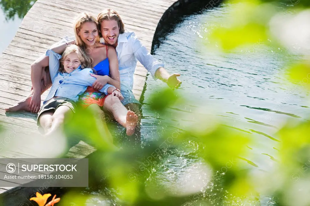 Austria, Salzburg County, Family sitting on bridge over natural pool