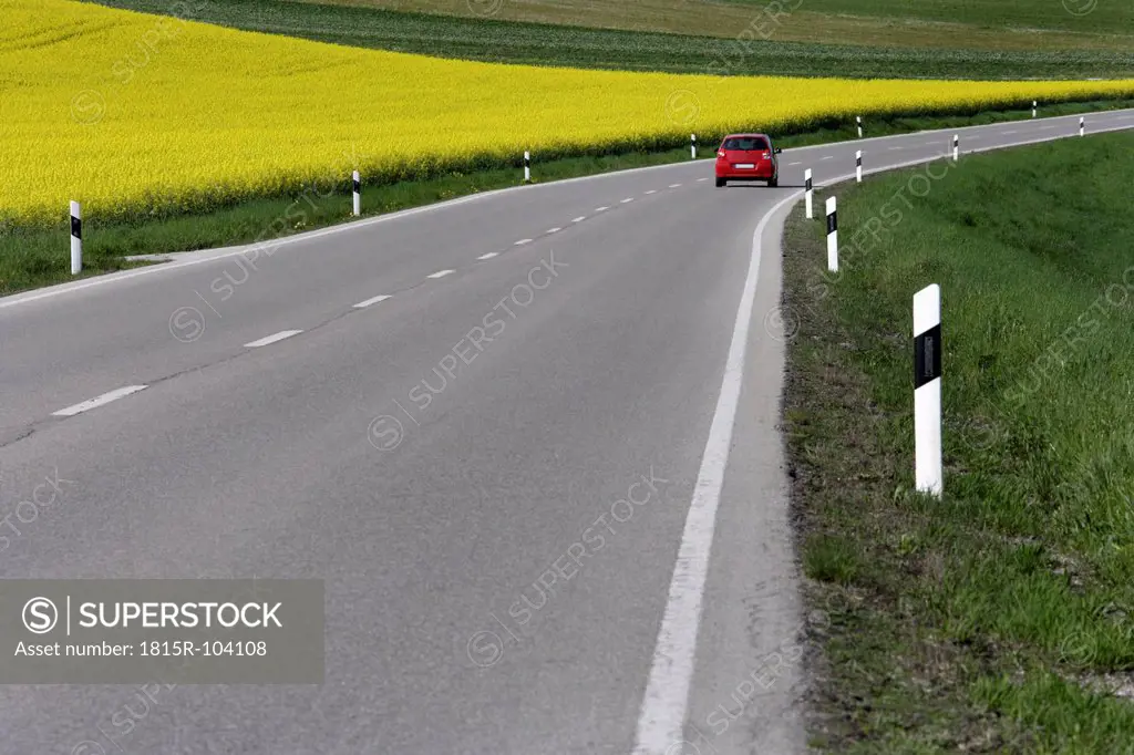 Germany, Bavaria, Car moving on road beside rape field