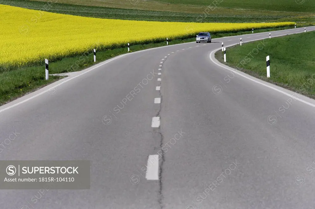 Germany, Bavaria, Car moving on road beside rape field