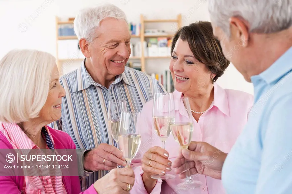 Germany, Leipzig, Senior men and women drinking sparkling wine, smiling