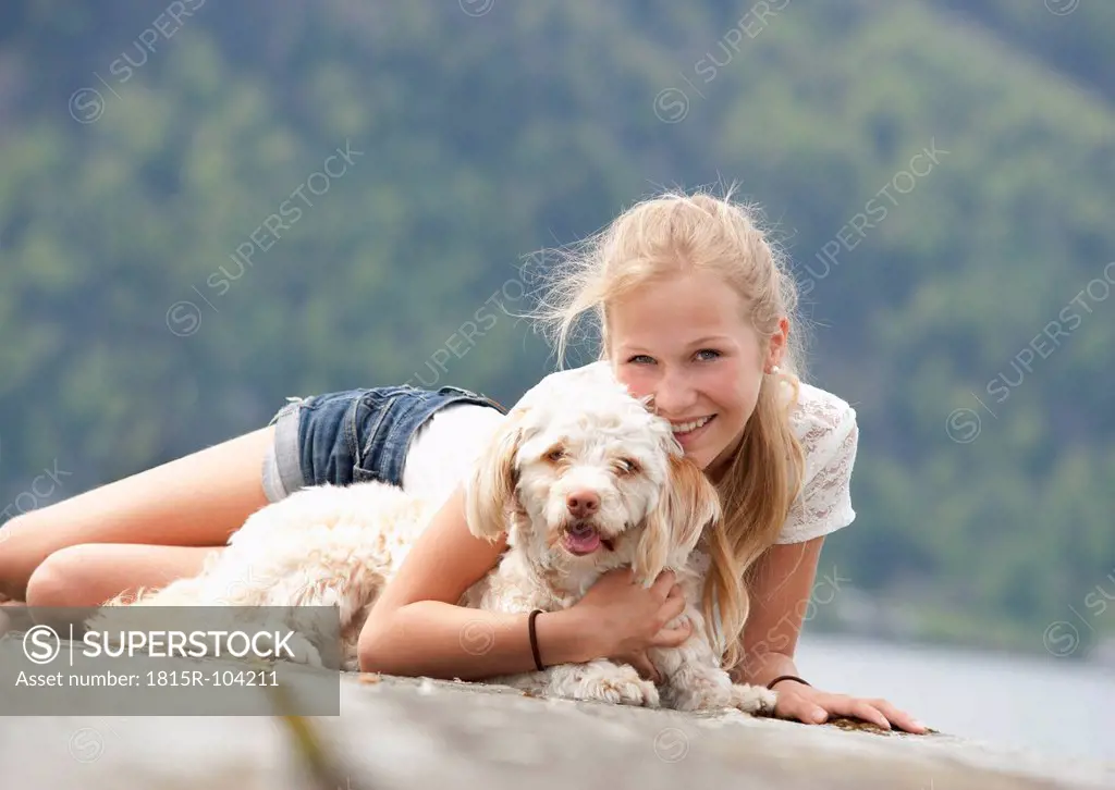Austria, Teenage girl with dog on jetty, smiling, portrait