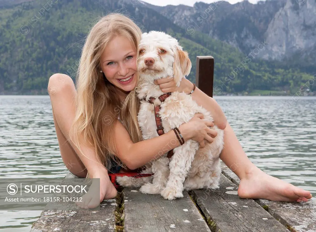 Austria, Teenage girl with dog on jetty, smiling, portrait