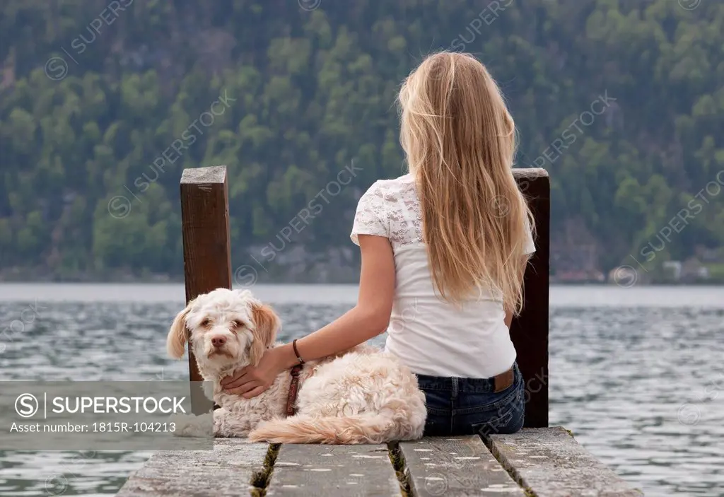 Austria, Teenage girl with dog on jetty