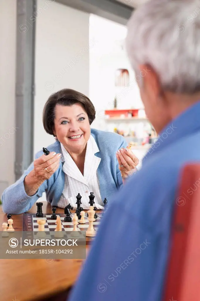 Germany, Leipzig, Senior man and woman playing chess game, smiling