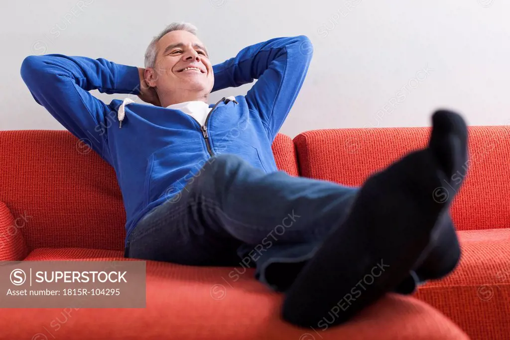 Germany, Leipzig, Senior man relaxing on couch, smiling