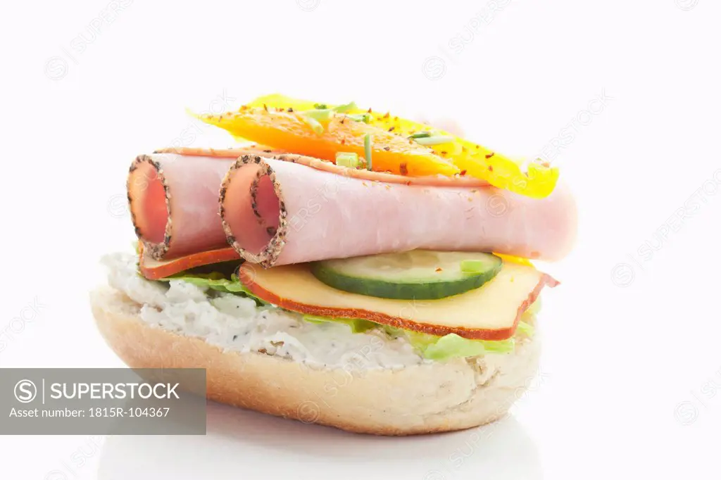 Bread roll with cooked ham, cheese, pepper, tomatoes, lettuce on white background