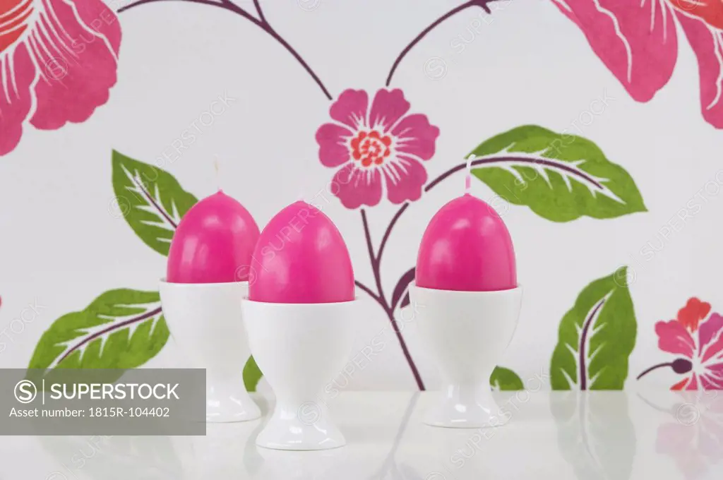 Egg shape candle in egg cup against floral pattern