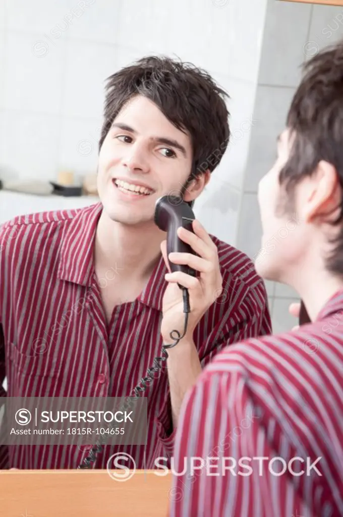 Young man doing shaving with electric razor