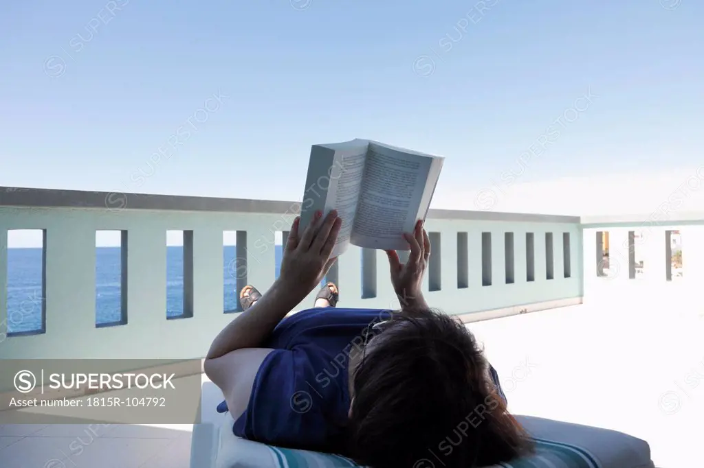 Spain, Canary Islands, La Palma, Mature woman reading book at balcony