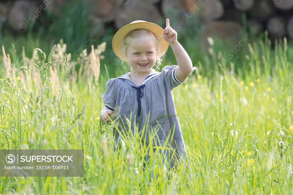 Germany, Bavaria, Girl standing in meadow, smiling, portrait