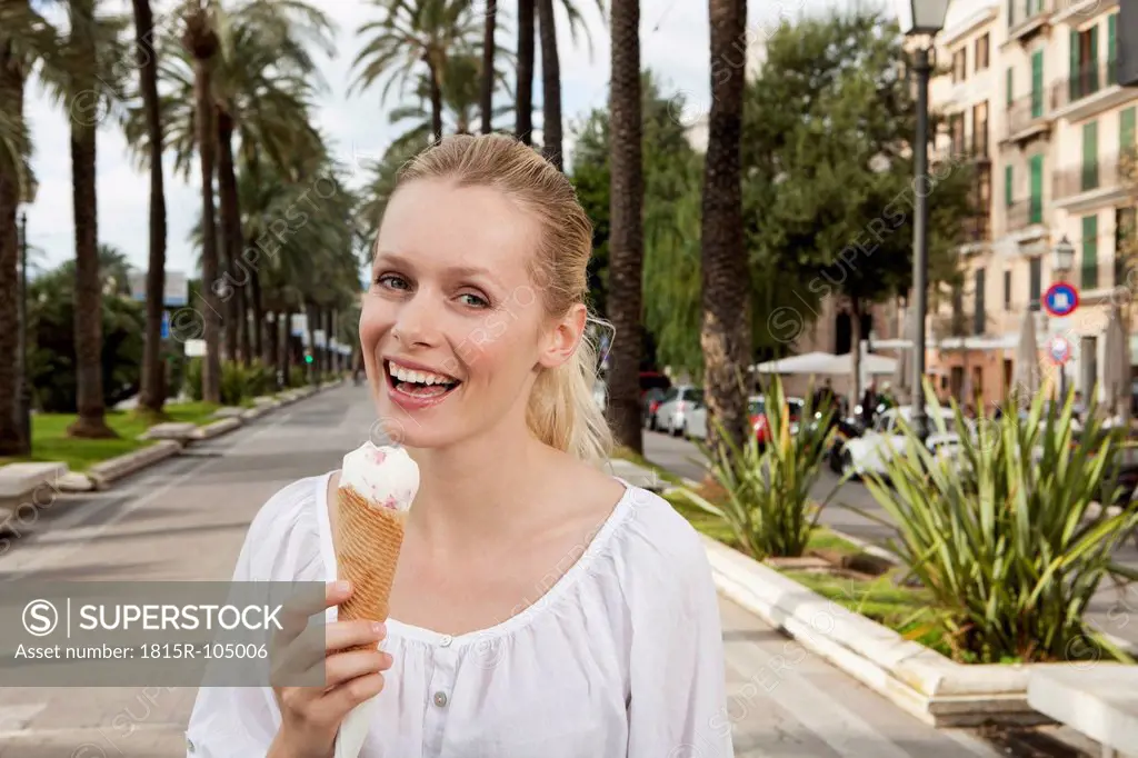 Spain, Mallorca, Palma, Young woman eating ice cream, smiling, portrait