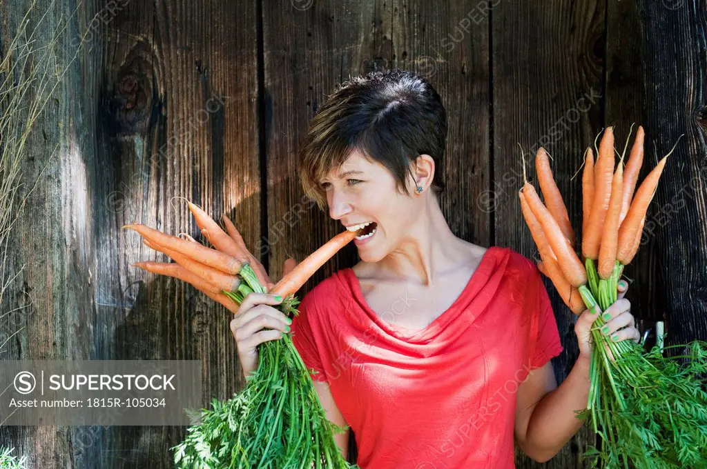 Austria, Salzburg, Flachau, Young woman holding carrots