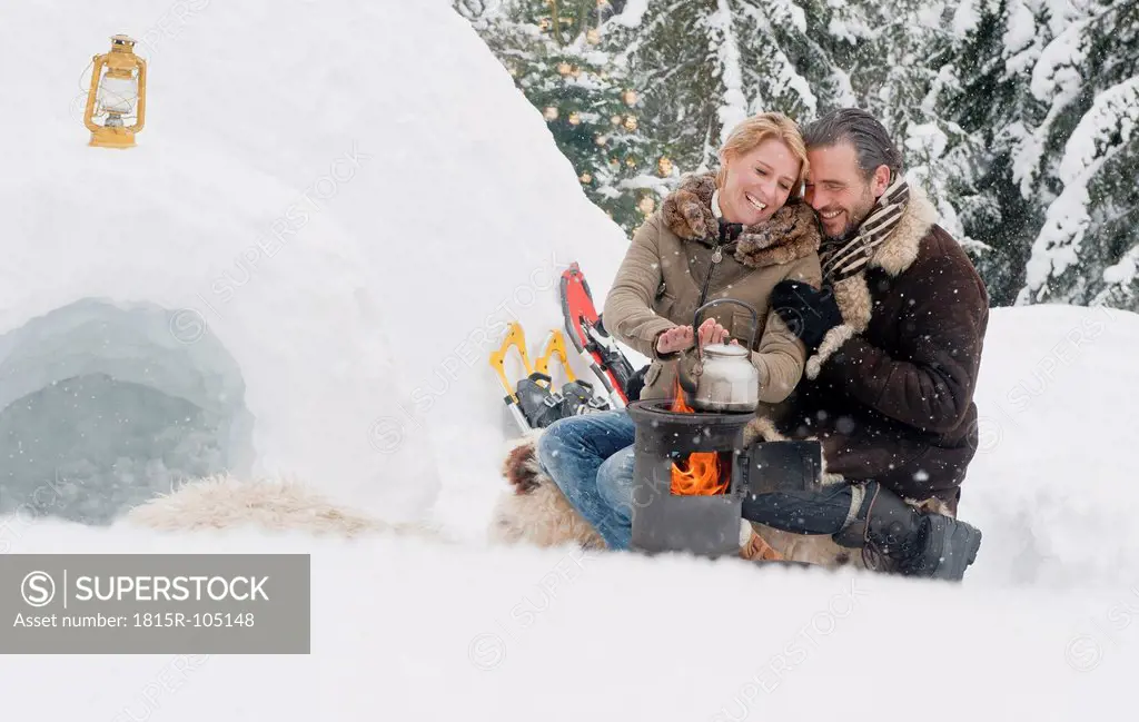 Austria, Salzburg County, Couple sitting near fireplace, smiling