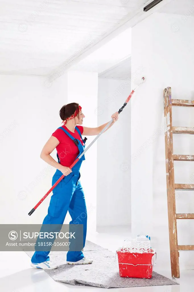 Germany, Bavaria, Young woman painting with paint roller
