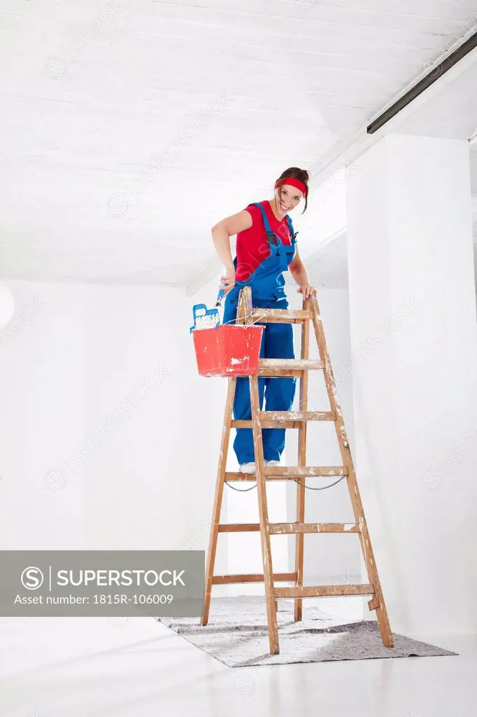Germany, Bavaria, Young woman on step ladder and painting