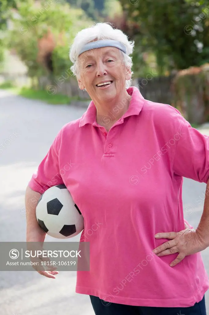 Germany, Bavaria, Huglfing, Senior woman with soccer ball, smiling, portrait