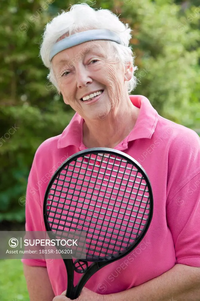 Germany, Bavaria, Huglfing, Senior woman holding badminton racket, smiling, portrait
