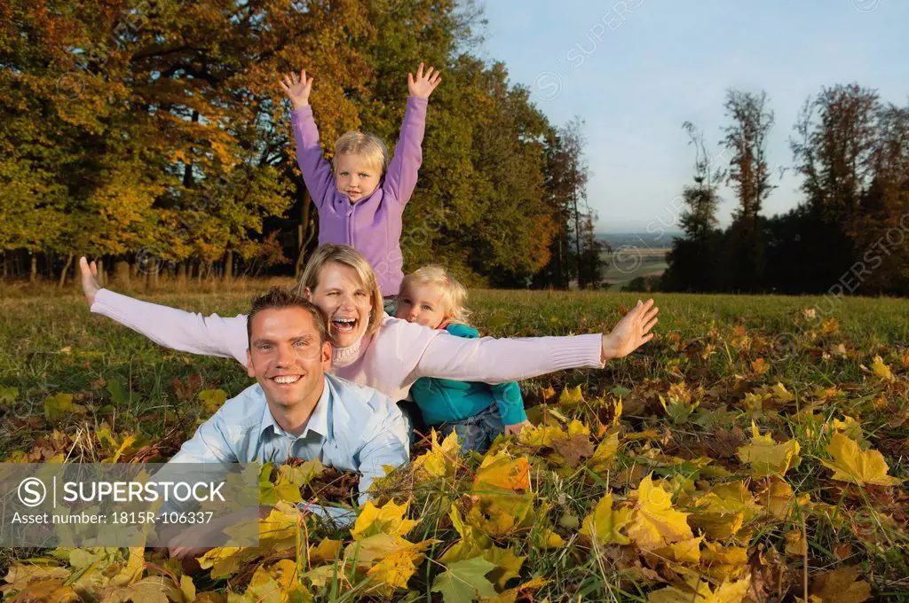 Germany, Bavaria, Family lying on leaves during autumn, portrait, smiling