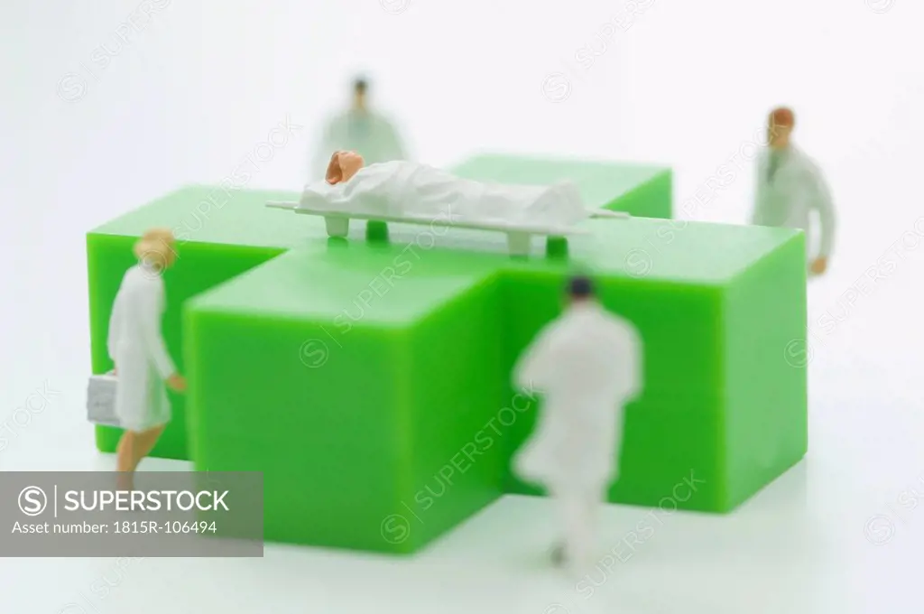 Figurines of doctors and patient with green medical symbol