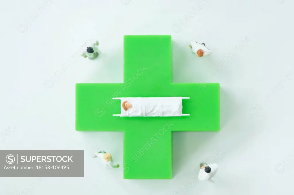 Figurines of doctors and patient with green medical symbol