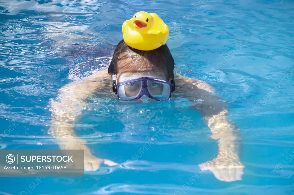 Man swimming with a rubber duck on his head