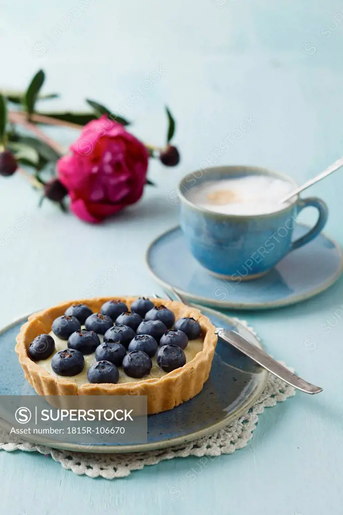 Blueberry tart with vanilla pudding and cappuccino on table